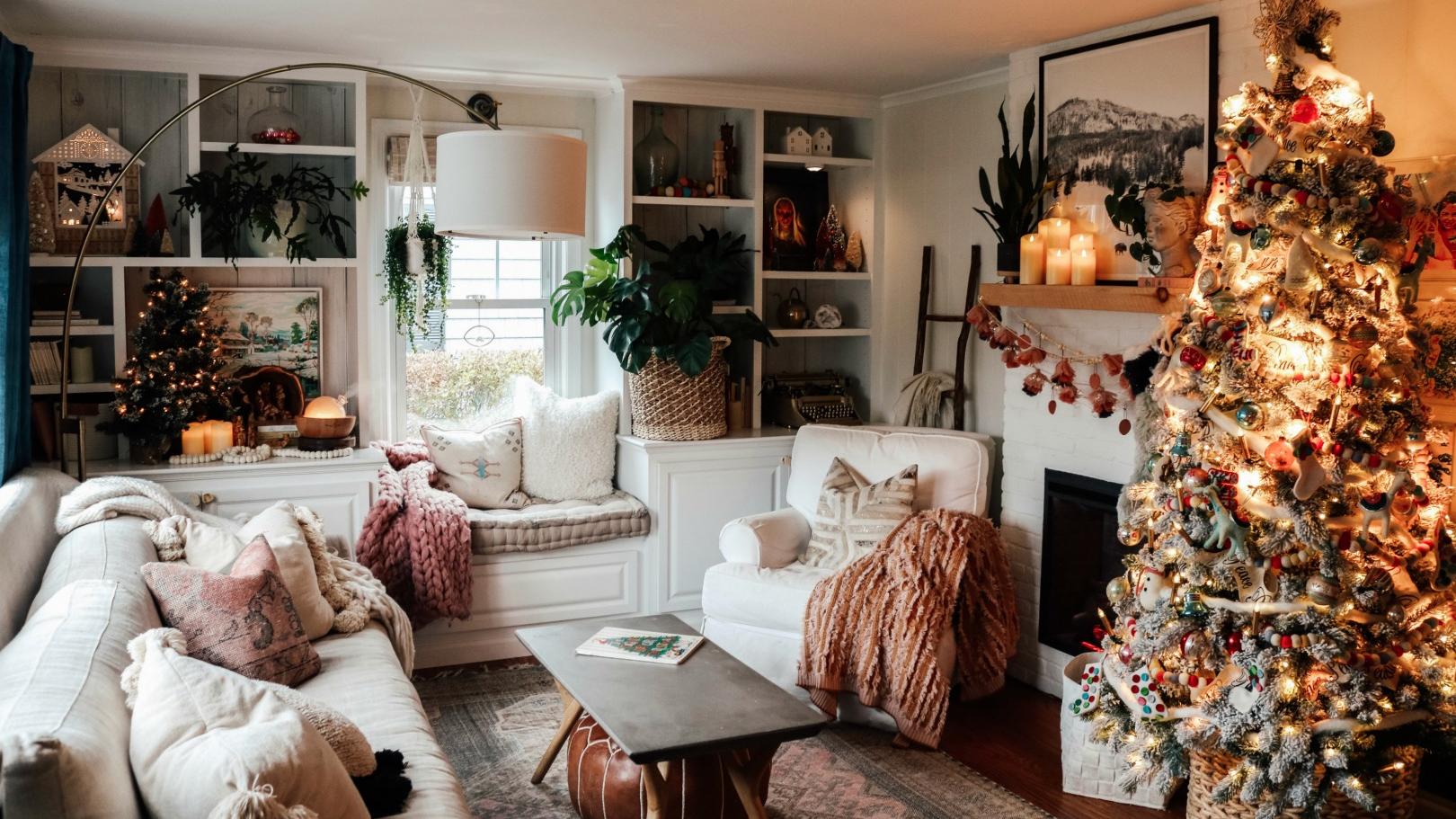 A cozy living room decorated for Christmas, featuring a brightly lit Christmas tree, a fireplace with a mantel display, and comfortable seating. Warm-toned decorations and soft textiles create a welcoming atmosphere.