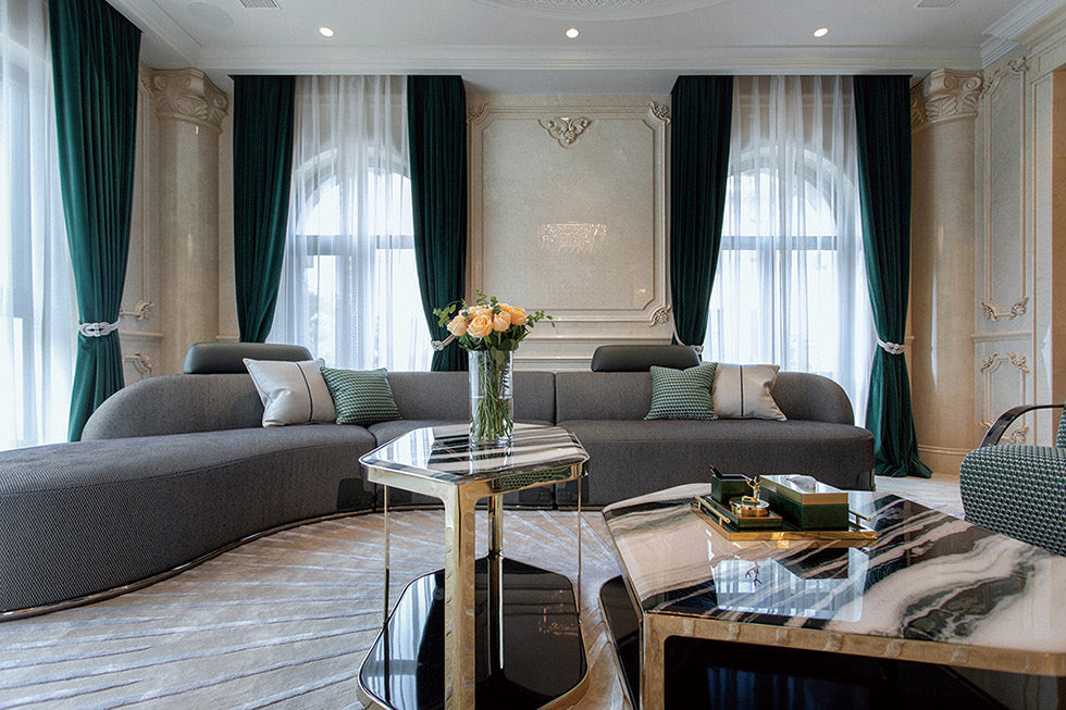 Cropped project view of veined tabletops with reflective edging in front of the grey sofa